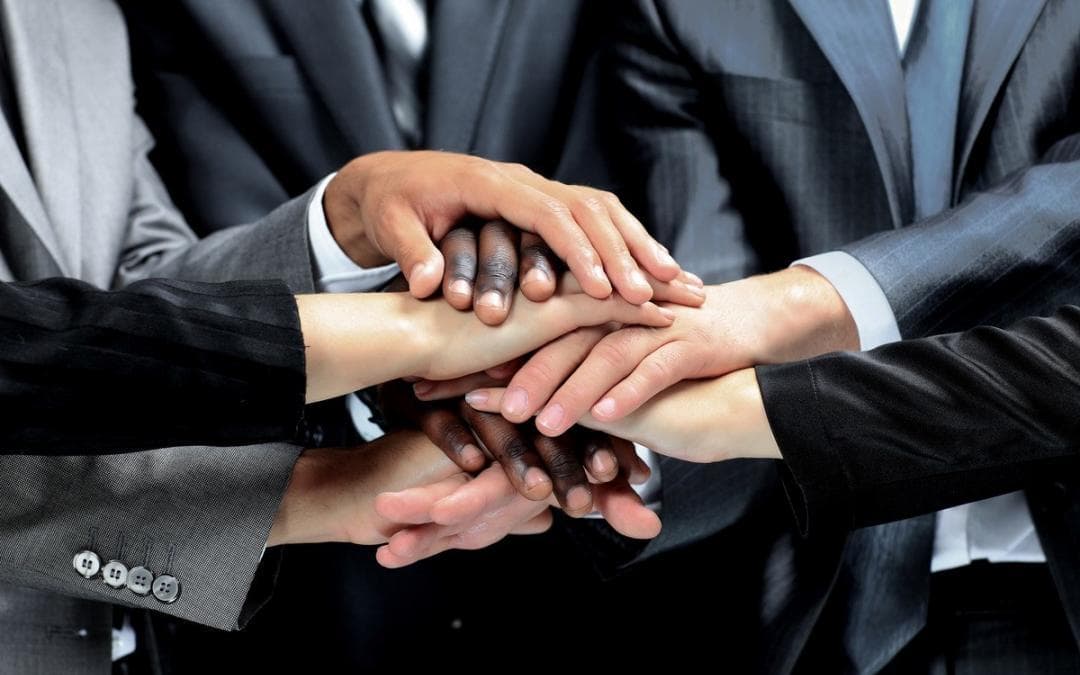 Líder e equipe reunidos ao redor de uma mesa, discutindo estratégias com postura colaborativa e hierárquica visível.